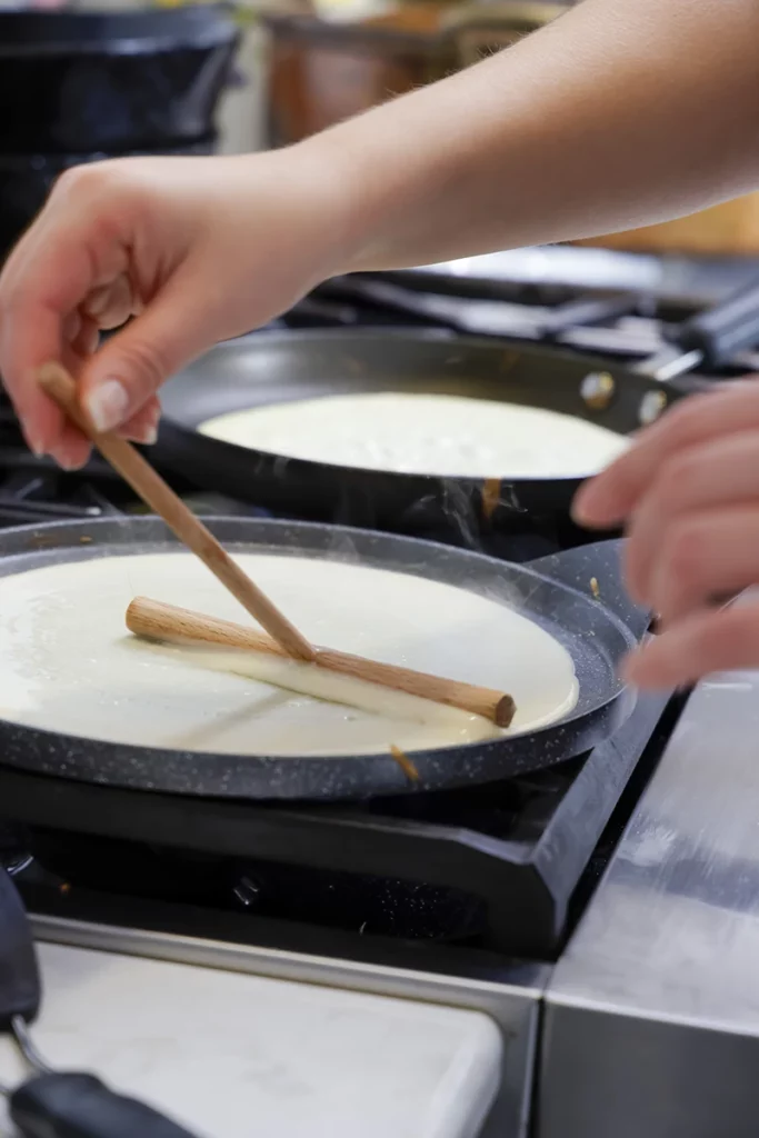 A hand making crepes.