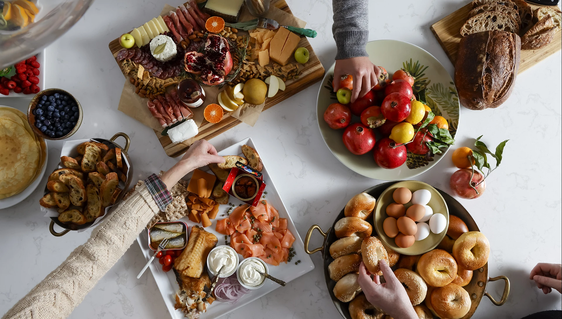 A table full of food with hands grabbing food.