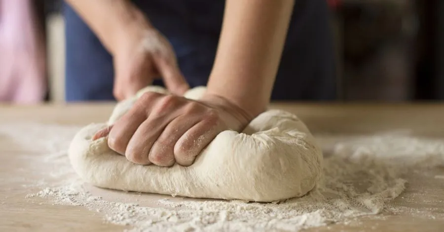 person making coco bread dough