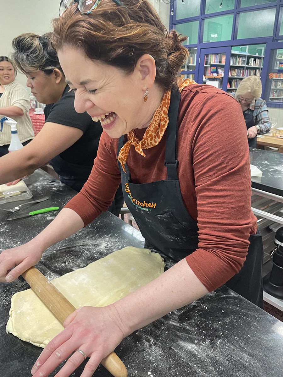 A woman rolling out dough and laughing