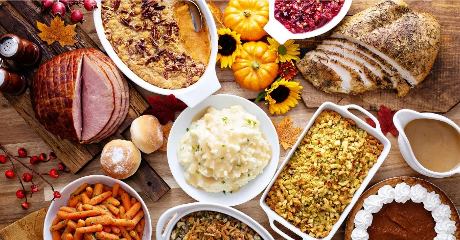 A table with thanksgiving sides including rolls and cranberry sauce.